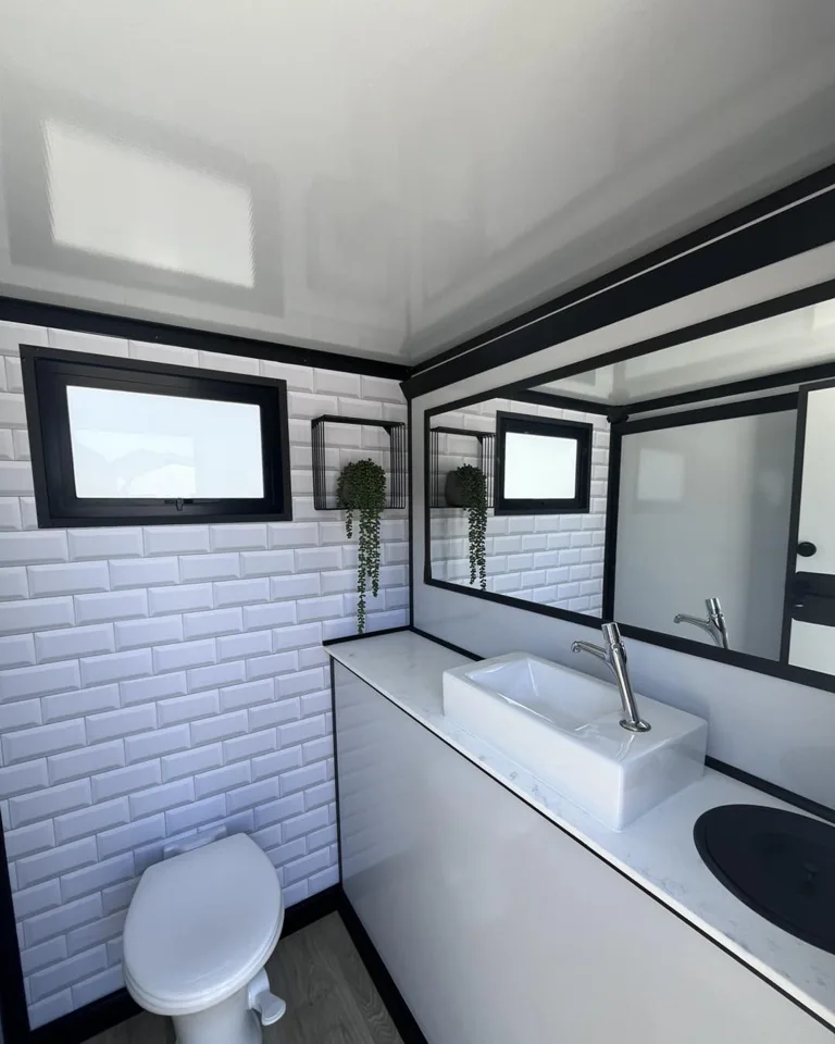 Restroom trailer interior with sink, mirror and toilet