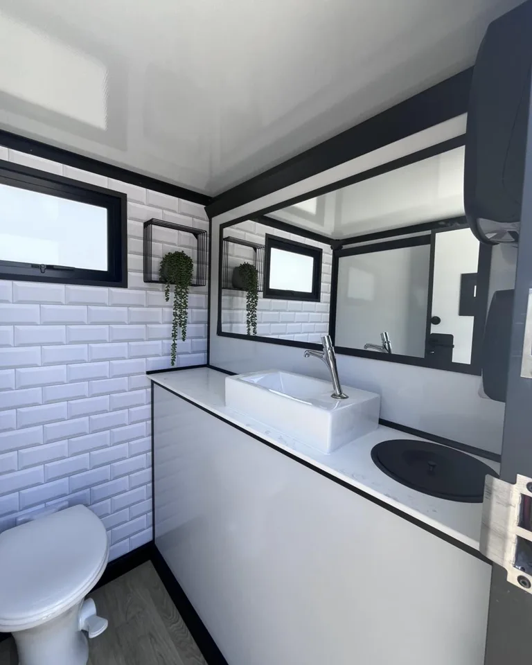 Restroom trailer sink and mirror with a toilet at the far end